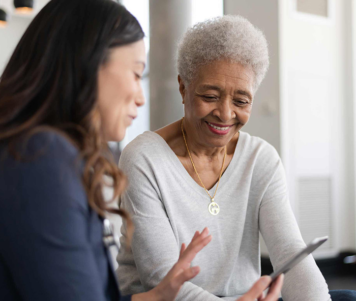a woman and her doctor talk while looking at a phone